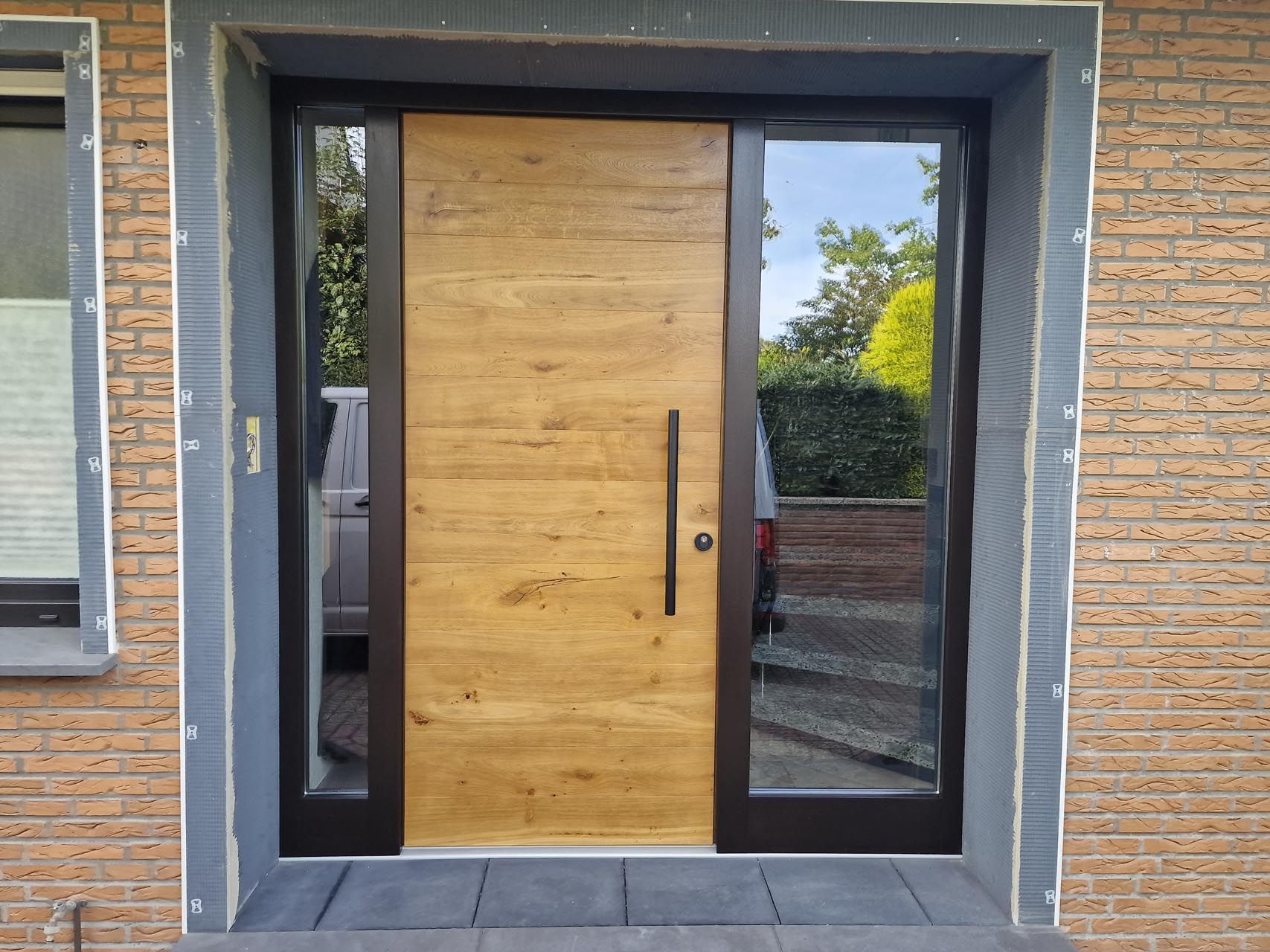 Ein Backsteingebäude mit einer Holztür und Glastüren von Hubert Uppenkamp GmbH