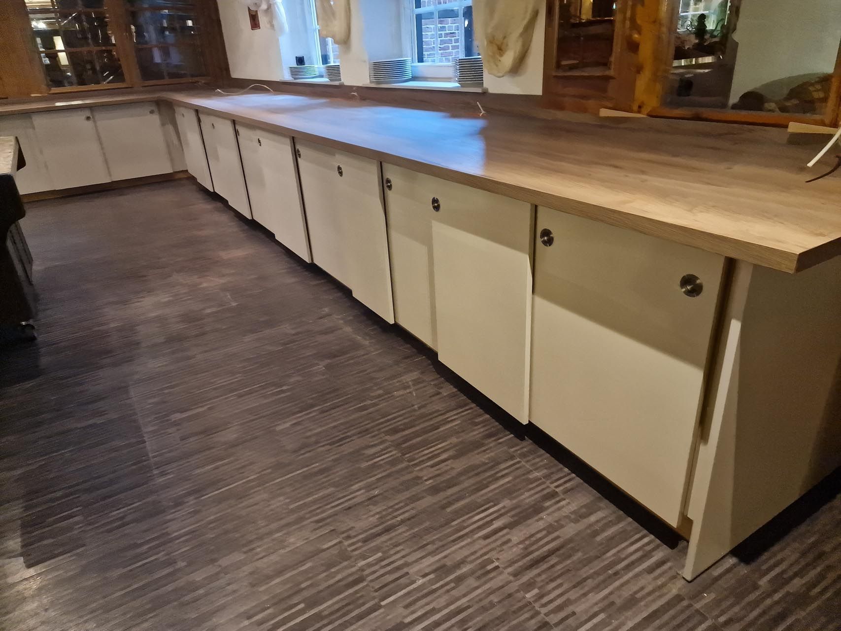 Eine Küche mit weißen Schränken und einer Arbeitsplatte aus Holz von Hubert Uppenkamp GmbH