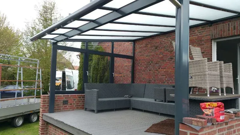 Eine Terrasse mit Sofa und Stühlen unter einem Baldachin.