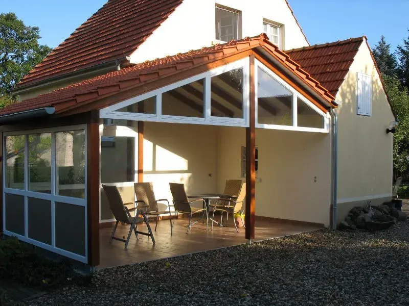 Ein Haus mit einer überdachten Veranda mit Stühlen und Tischen