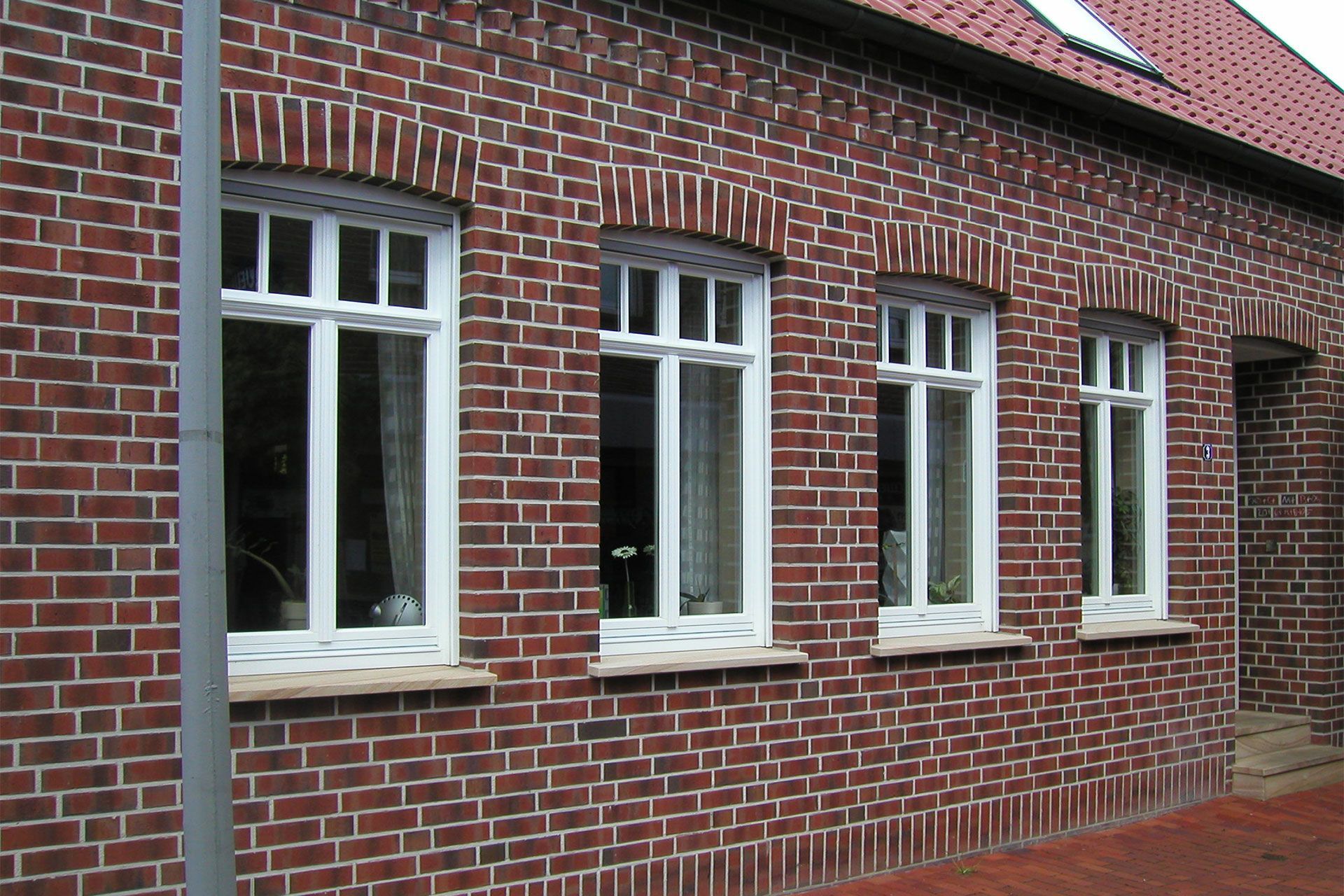 Ein rotes Backsteingebäude mit drei weißen Fenstern