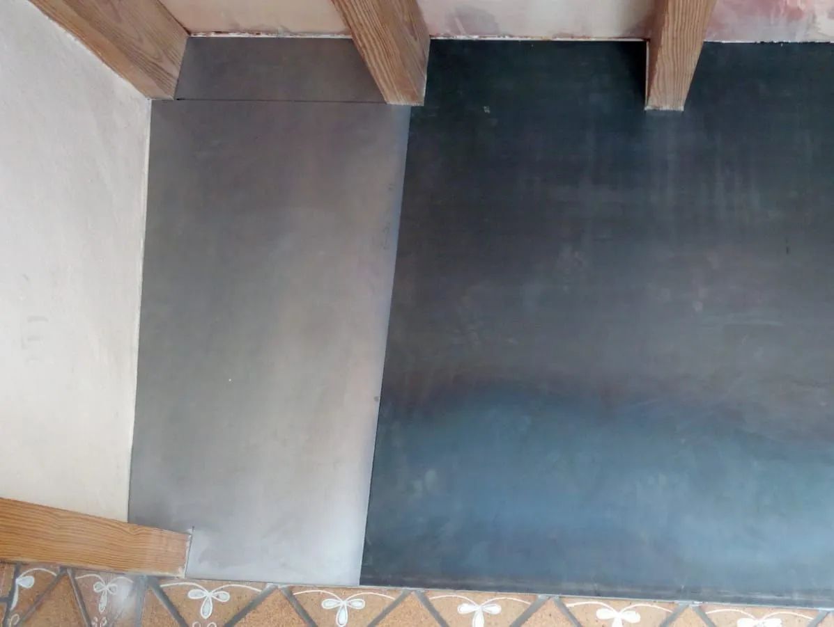 Pared interior con vigas de madera a la vista y dos secciones pintadas, una de color gris claro y otra de color azul oscuro.