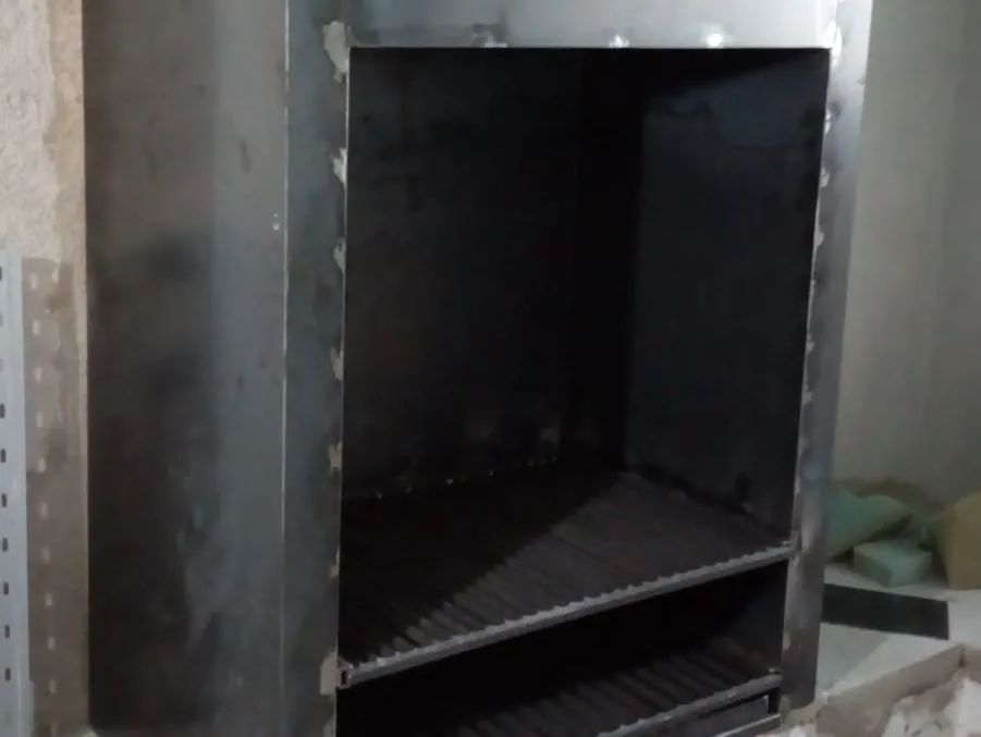 Armario o rejilla de ventilación de metal negro con interior oscuro en una pared de hormigón.