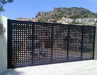 Puerta de metal perforado negro con vista a la montaña al fondo.
