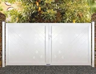 Puerta doble de jardín blanca con pestillo central, enmarcada por pilares de piedra y vegetación en la parte superior.