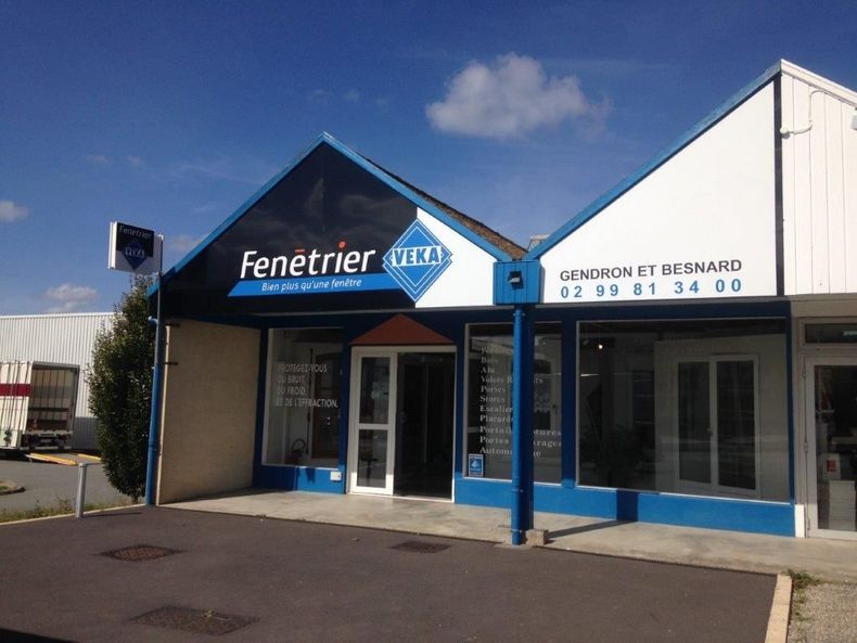 Façade du bureau Fenetrier avec auvents bleus et portes vitrées sous un ciel dégagé