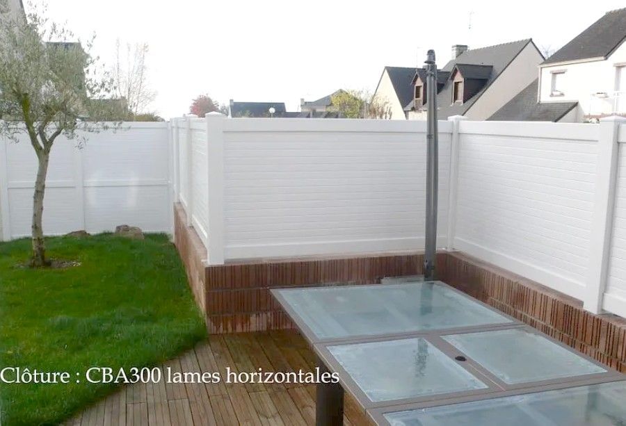 Terrasse arrière avec clôture blanche pour plus d'intimité, pergola grise et coin salon en bois.