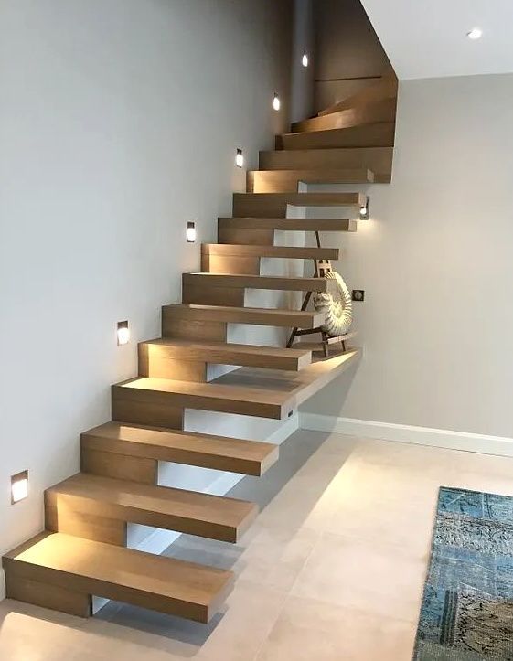 Escalier flottant moderne en bois avec éclairage intégré sur les marches dans une pièce minimaliste ; petit chien assis sur une marche