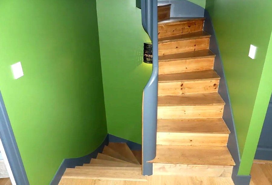 Escalier vert avec marches en bois et rampe bleue incurvée