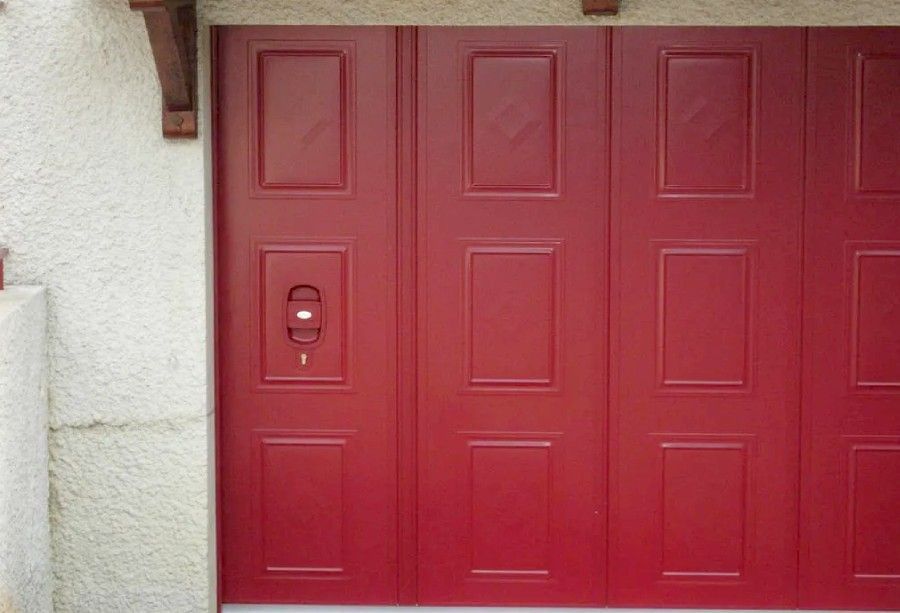 Porte de garage rouge avec une petite serrure à clavier numérique sur le côté gauche.
