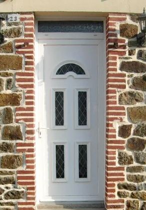 Porte d'entrée blanche avec panneaux de verre décoratifs encastrés dans un cadre en pierre