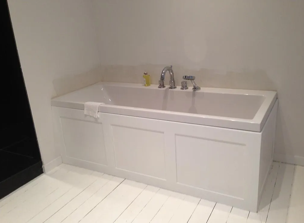 Meuble-lavabo blanc avec vasque intégrée, robinet chromé et sol carrelé contre un mur clair