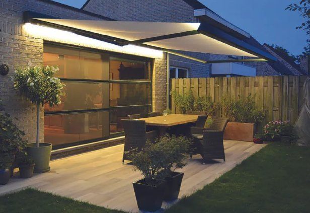 Terrasse moderne au crépuscule avec table à manger, chaises, plantes en pot et éclairage extérieur chaleureux