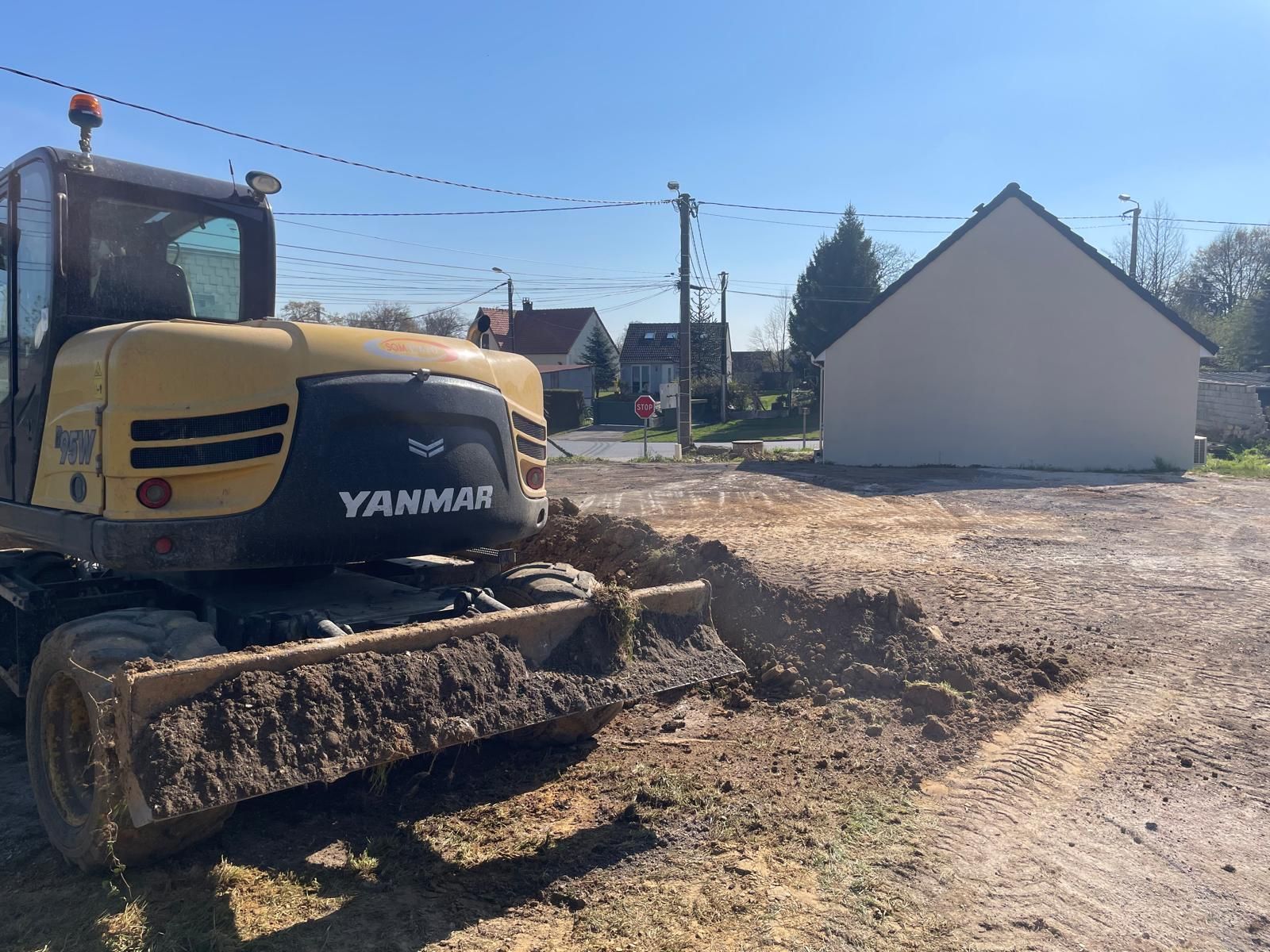 Un bulldozer Yanmar jaune est garé dans un champ de terre.