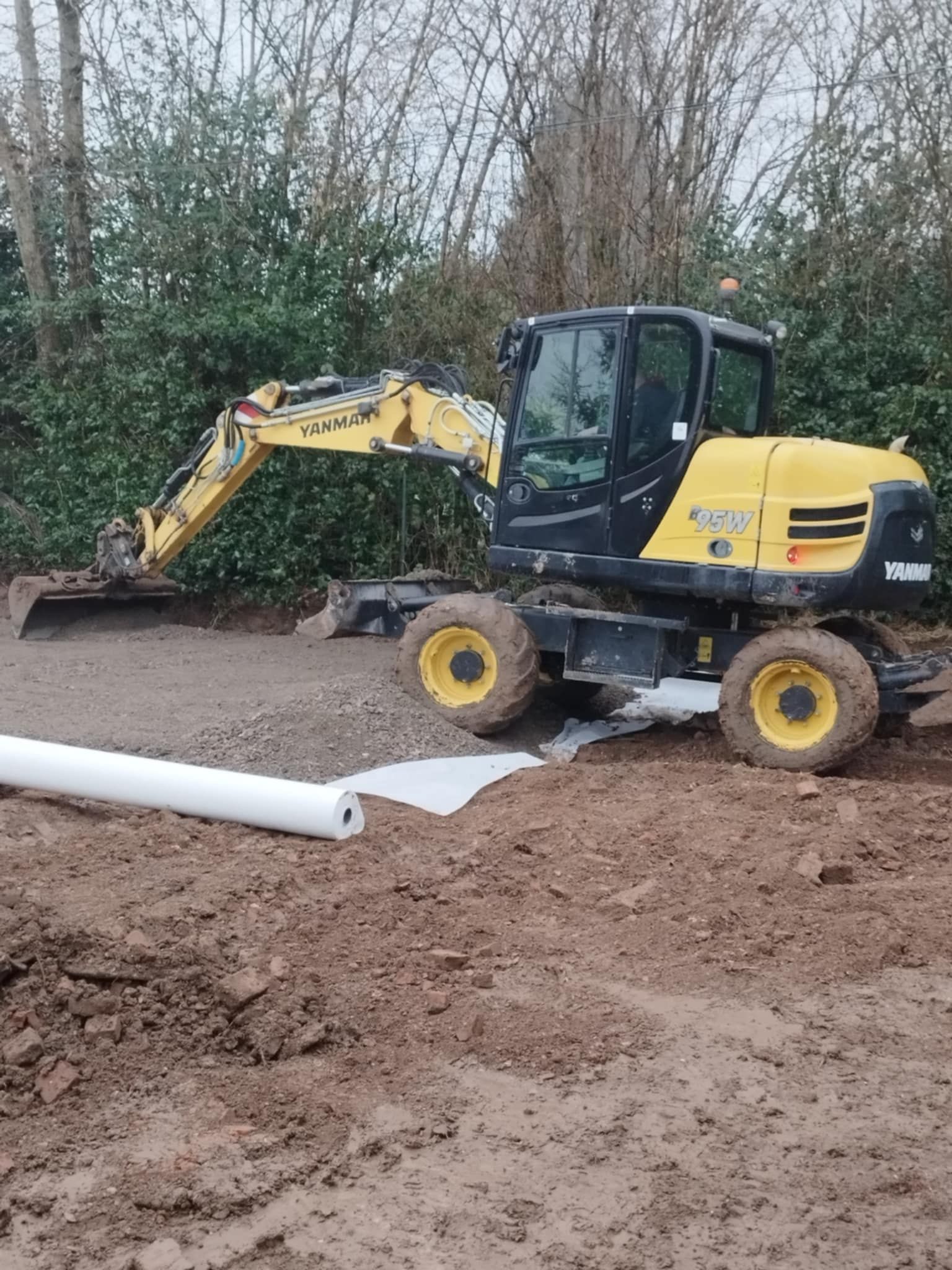 Une excavatrice jaune et noire est assise sur un champ de terre.