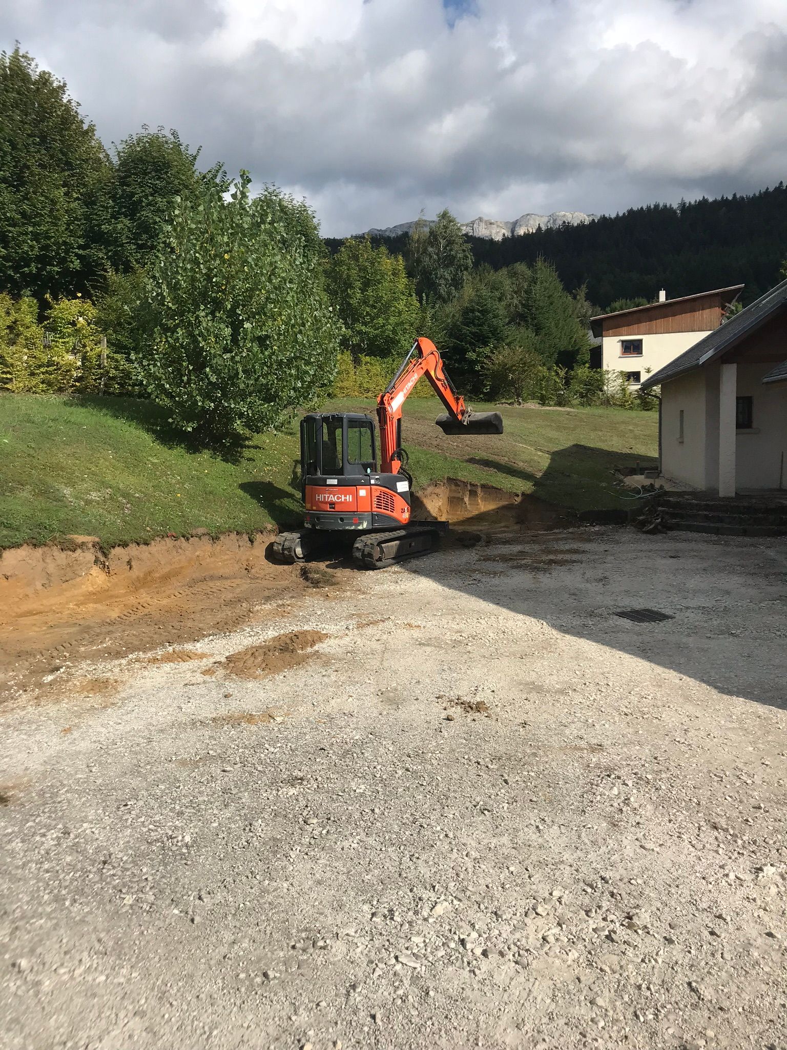 Petite pelleteuse orange creusant de la terre sur un terrain en pente.