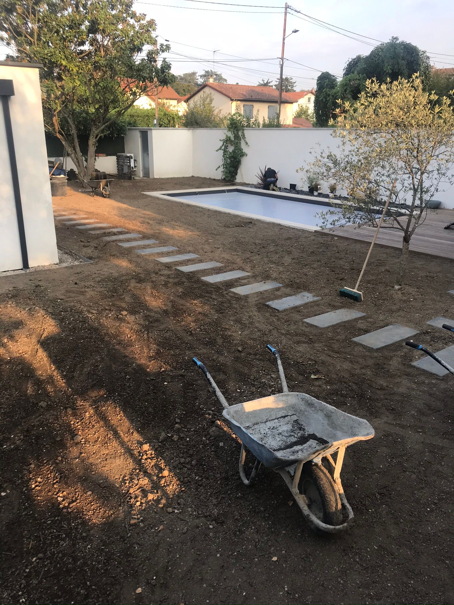 Un aménagement paysager récent avec des pas japonais et une piscine en arrière-plan.