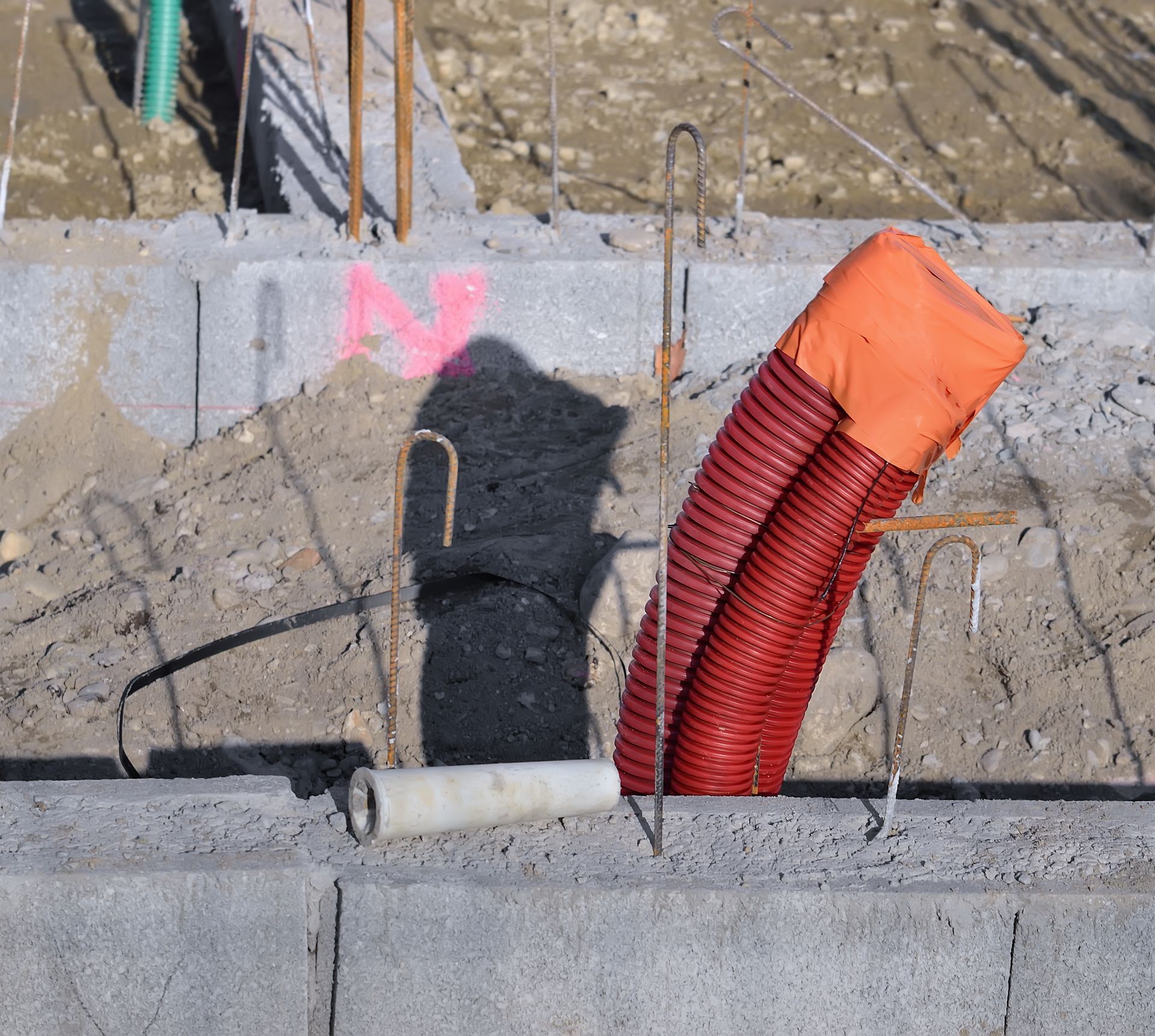 Chantier de construction avec des conduits rouges d'évacuation.