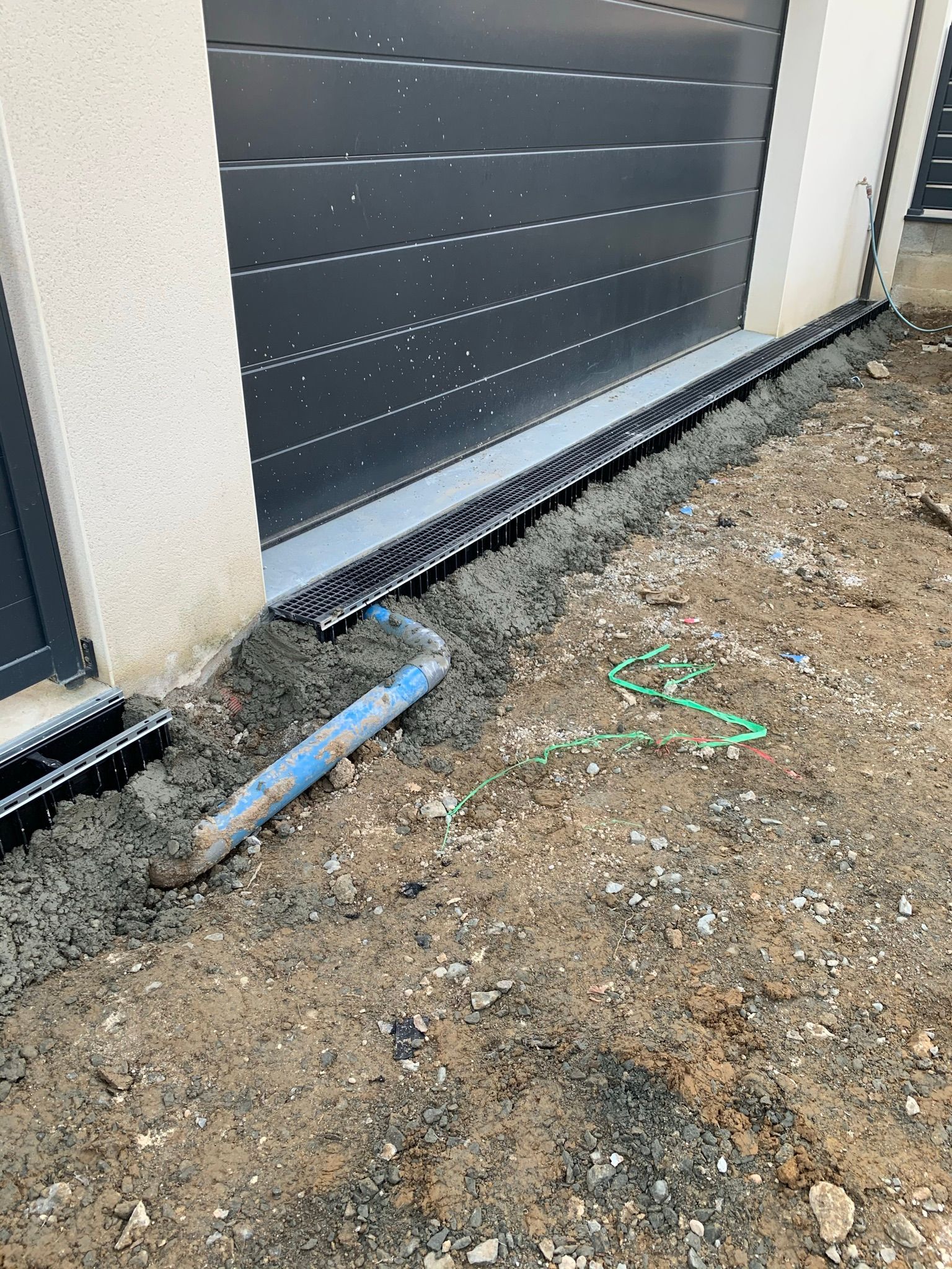 Une porte de garage avec une grille d'évacuation des eaux pluviales au niveau du seuil.