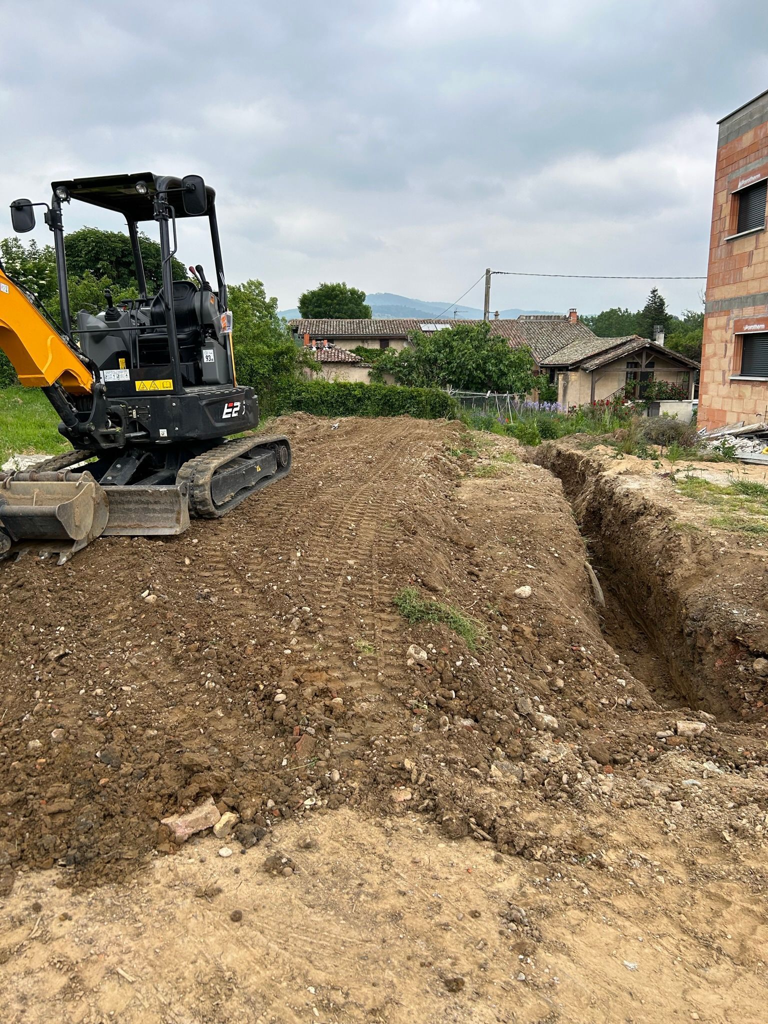 Minipelle creusant une tranchée sur un terrain.