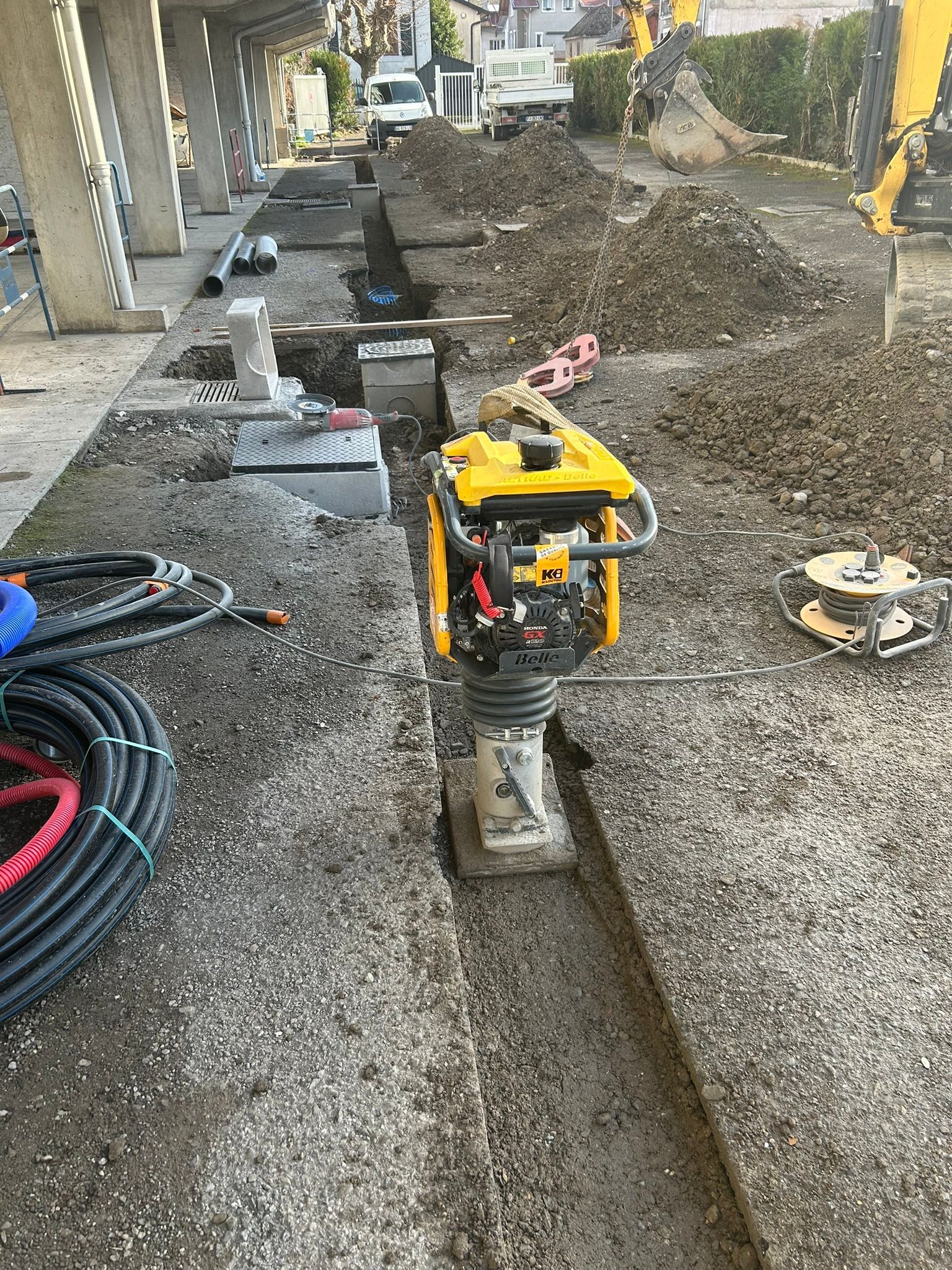 Un compacteur est utilisé dans une tranchée étroite tapissée de gravier.