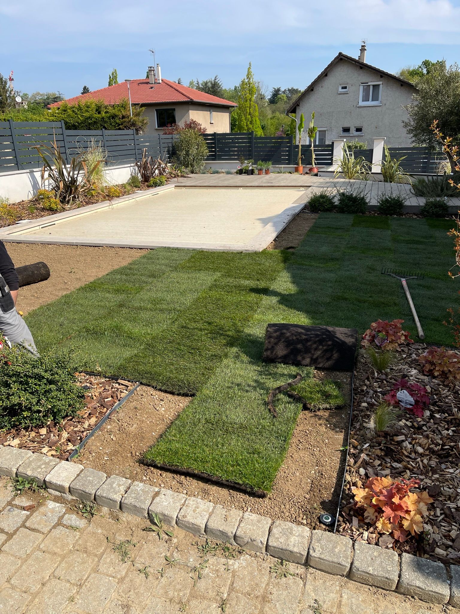 Pose de gazon en rouleaux dans un jardin résidentiel avec piscine.