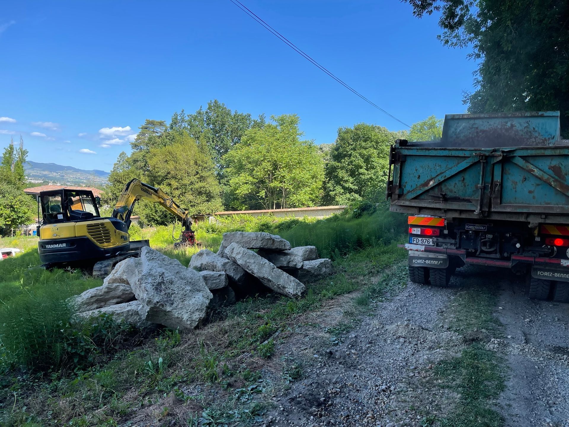 Un camion de chantier avec une pelleteuse et des pierres d'enrochement.