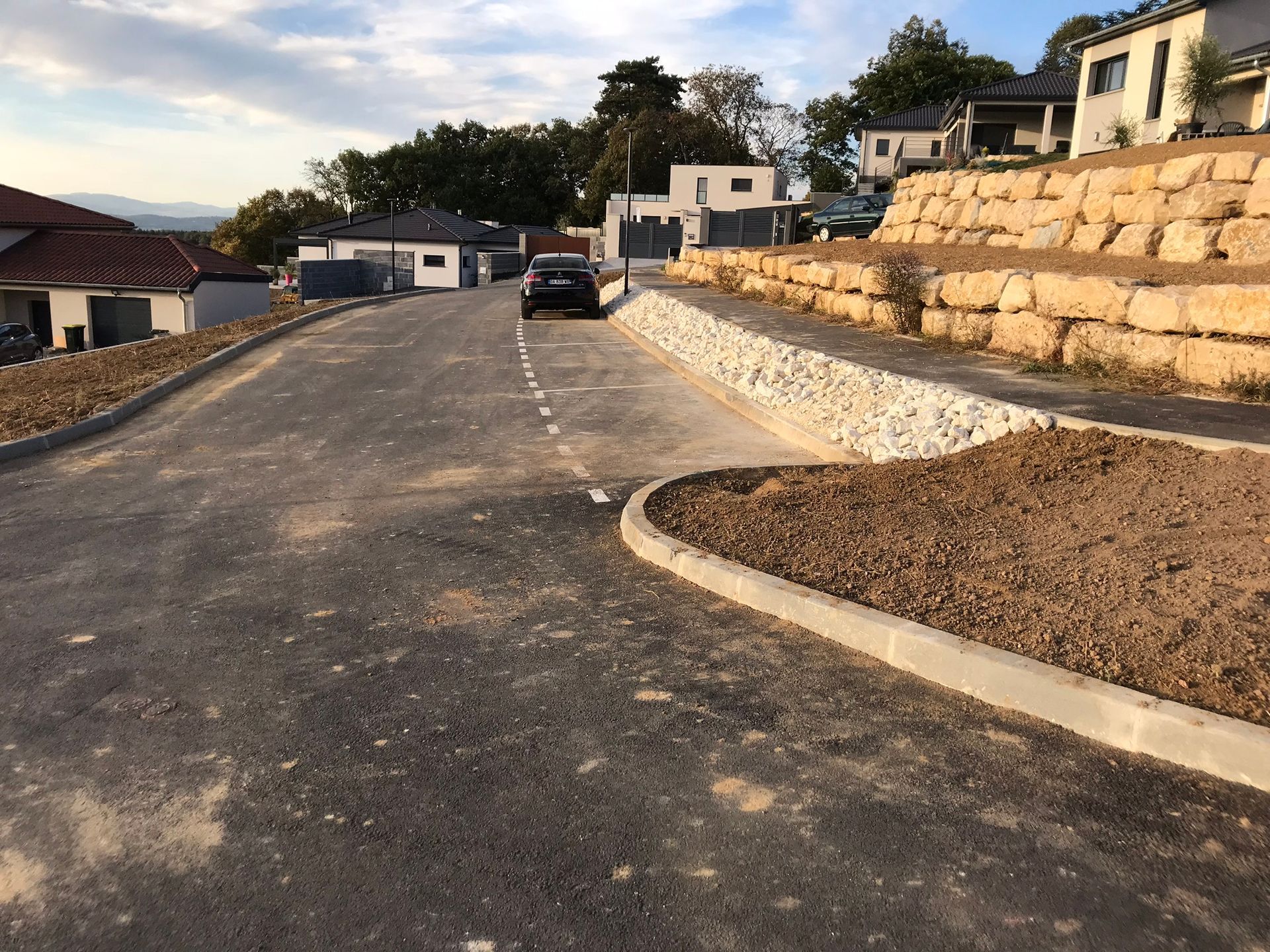 Un lotissement construit récemment avec une route goudronnée et des murs de soutènement sur le côté.