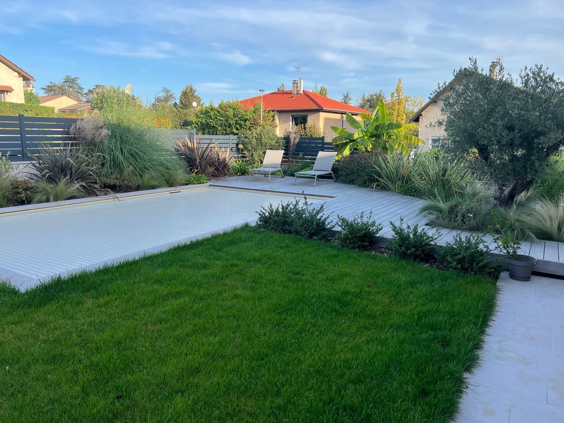 Un jardin avec une piscine et des transats.