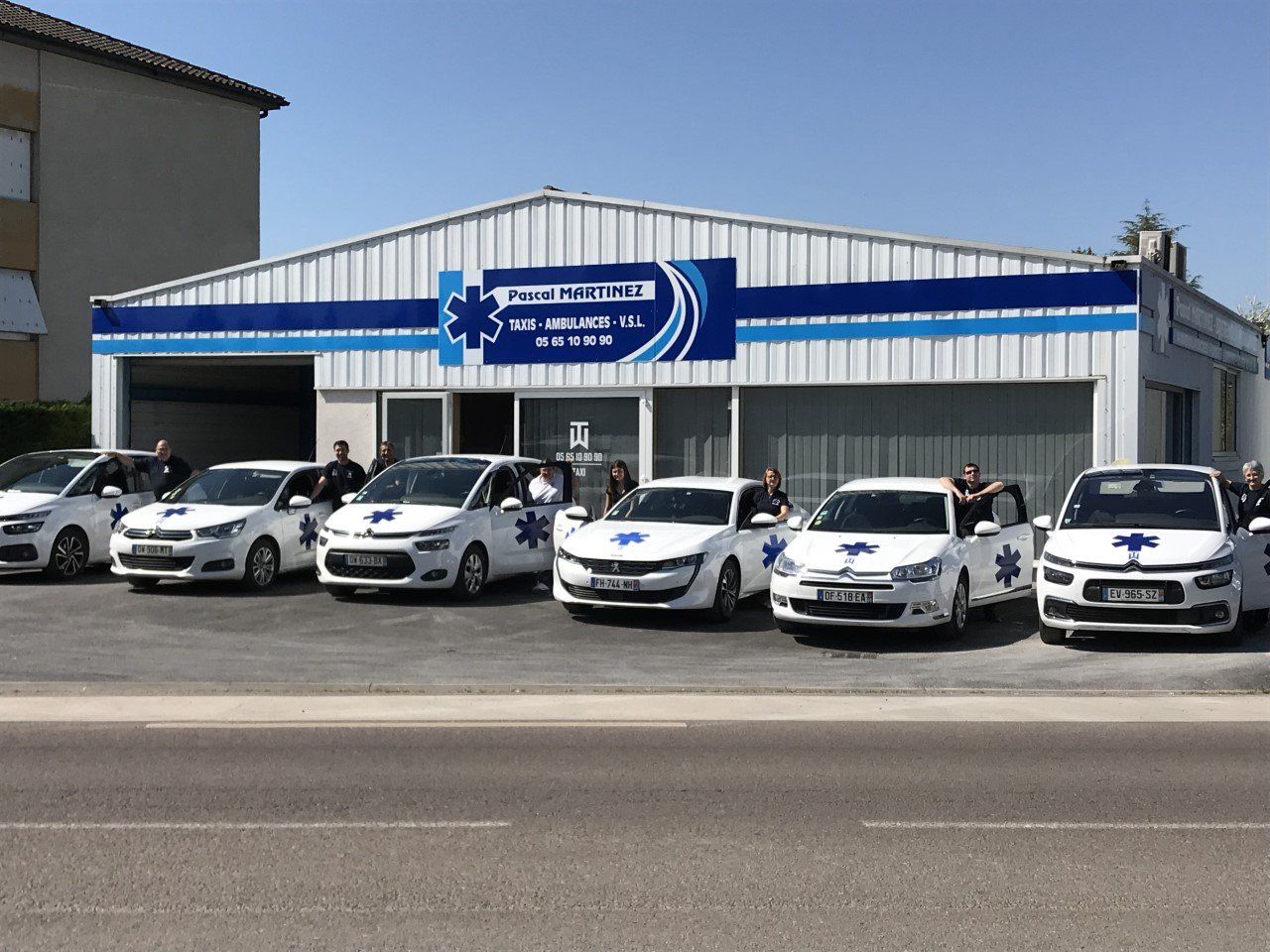 Plusieurs véhicules médicalisés et leurs chauffeurs devant les bureaux de l'entreprise