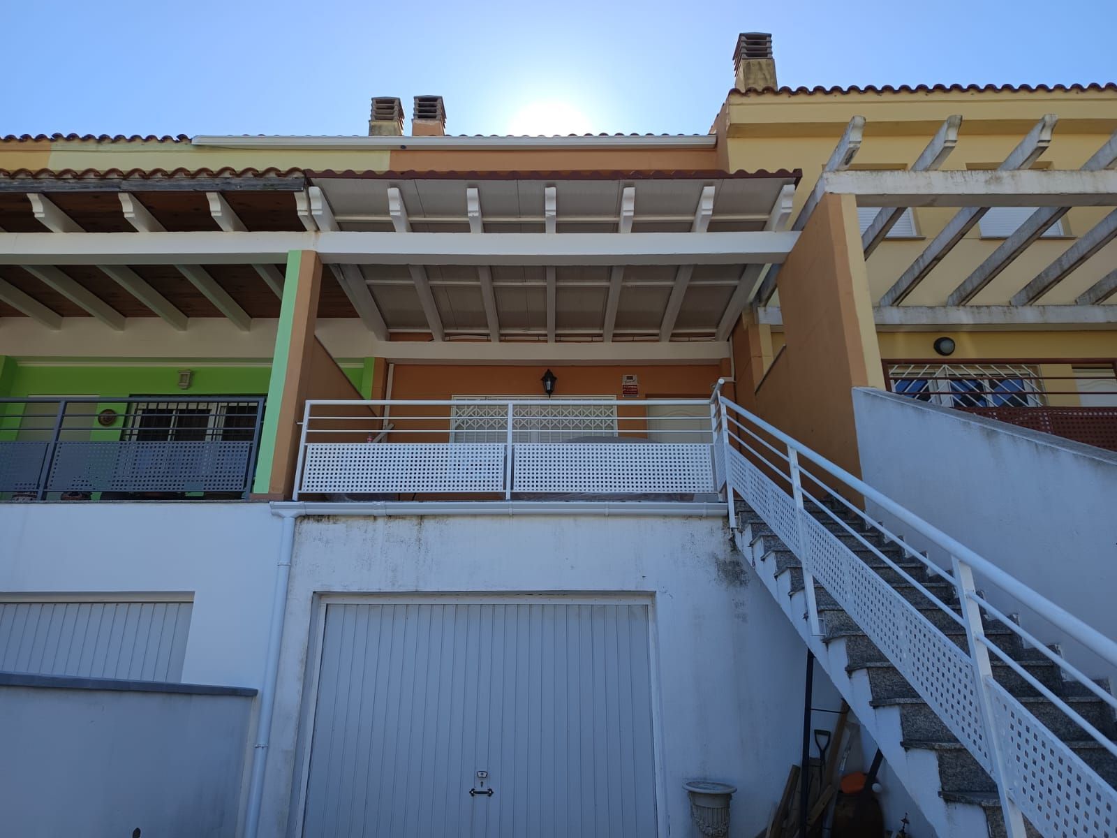Una casa adosada residencial con fachada naranja, balcón cubierto