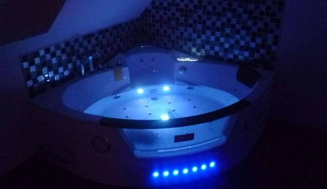 Baignoire d'angle équipée de jets hydromassants et d'effets lumineux.