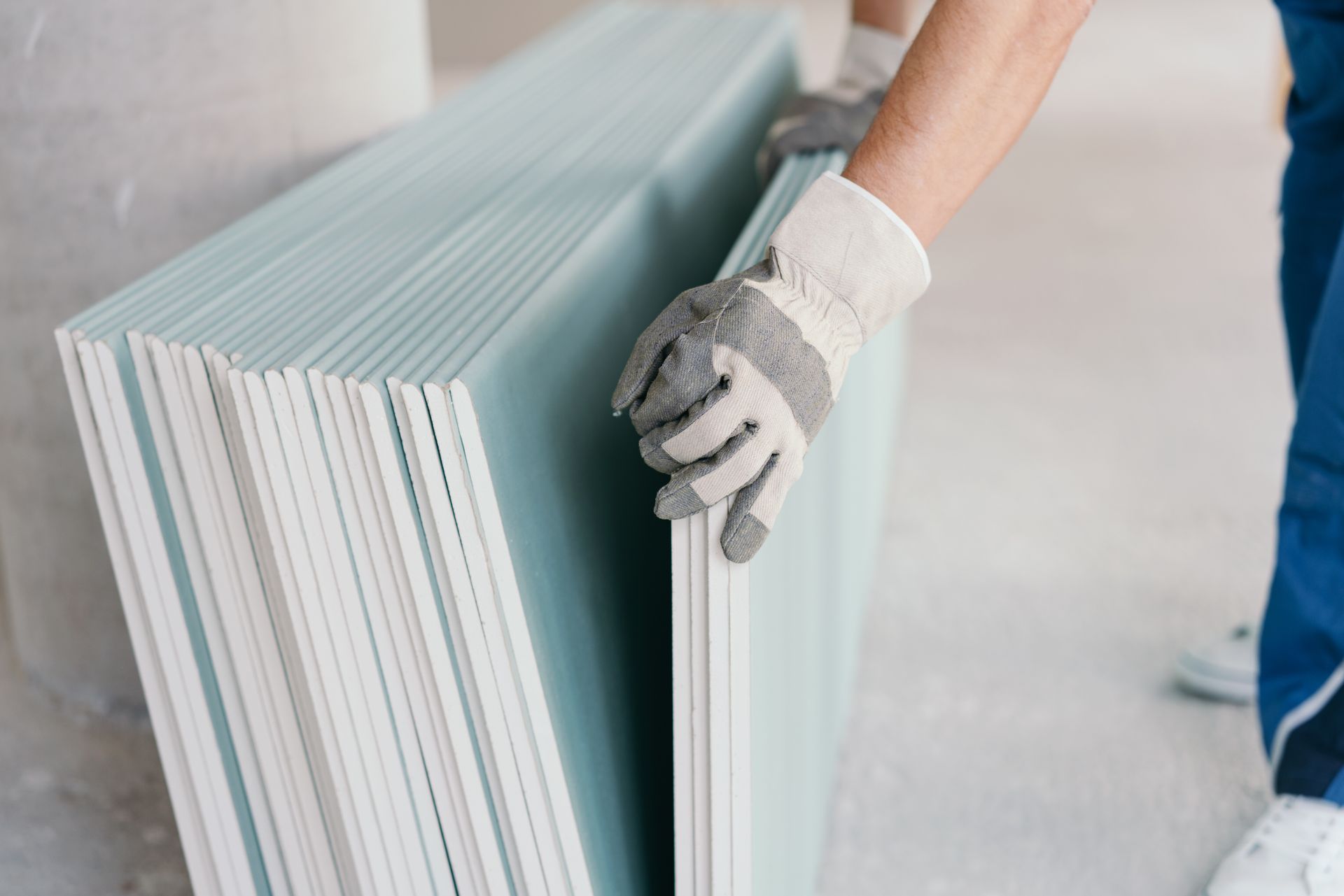 Un ouvrier pose plusieurs plaques de plâtres sur un mur.