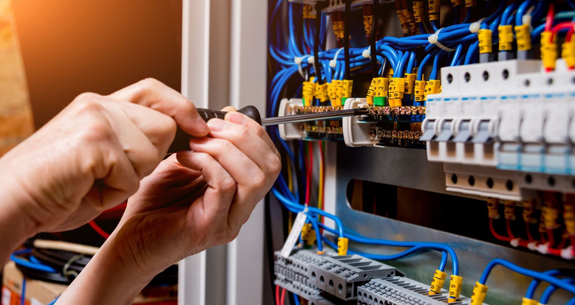 Une personne avec un tournevis dans un compteur électrique.