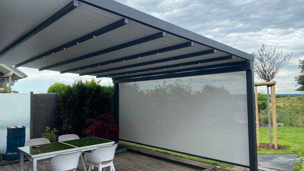 Eine Terrasse mit Tisch und Stühlen unter einem Baldachin.