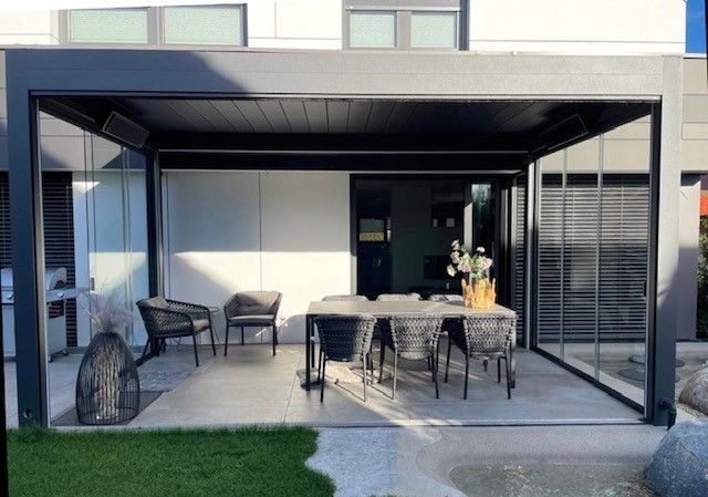 Eine Terrasse mit Tisch und Stühlen unter einer Pergola.