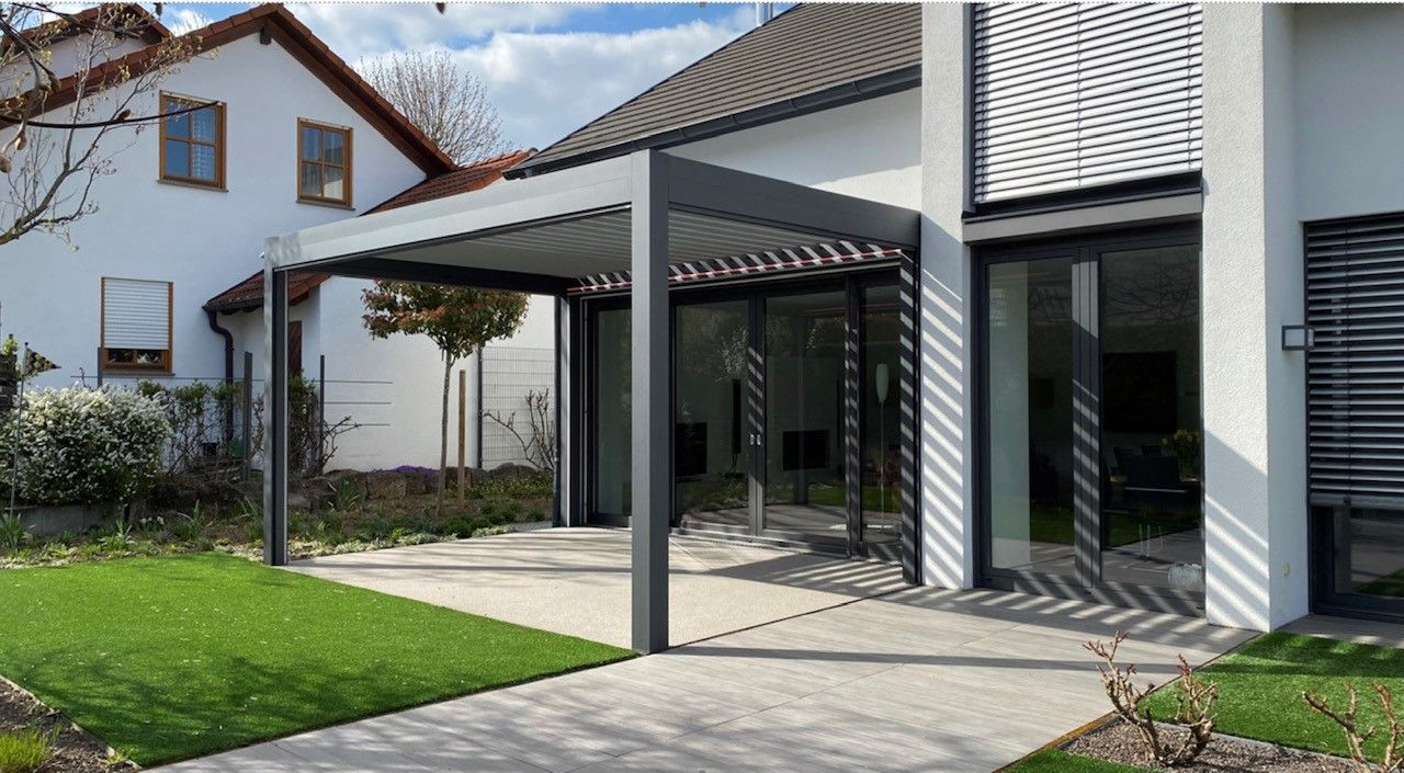 Ein weißes Haus mit einer Pergola davor.