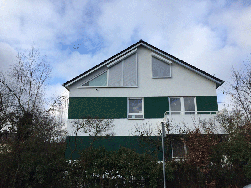 Ein grün-weißes Haus mit schrägem Dach