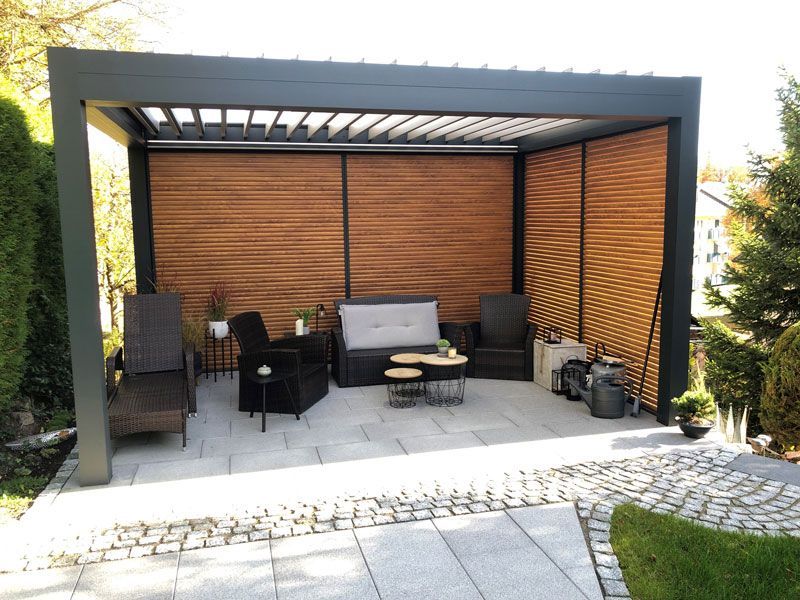 Eine Pergola mit einer Couch und Stühlen darunter