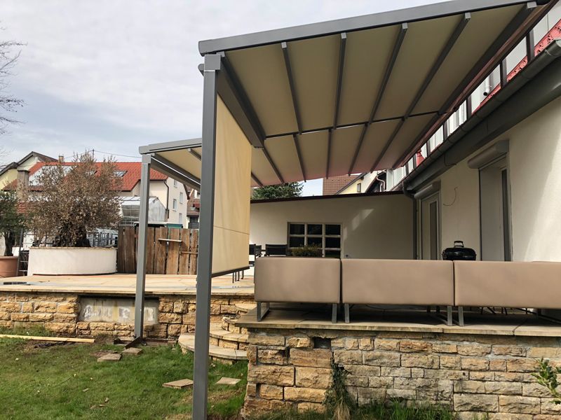 Eine Terrasse mit einem Vordach darüber und einer Backsteinmauer