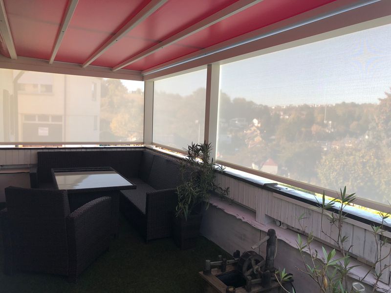 Eine Terrasse mit einer roten Markise und einem Tisch und Stühlen.