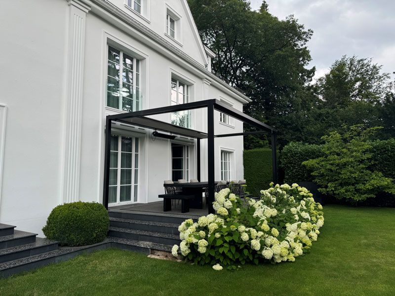 Ein großes weißes Haus mit einer Pergola im Hinterhof.
