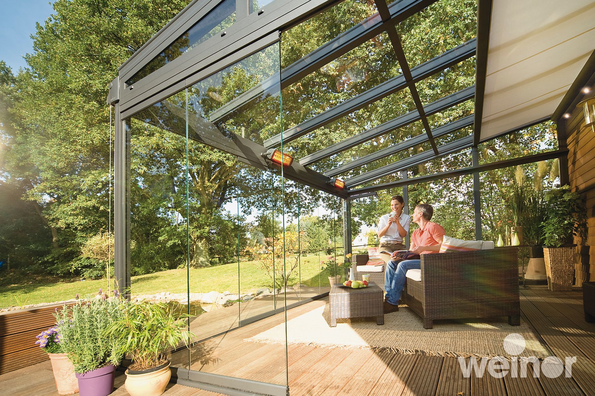 Ein paar Leute sitzen auf einer Terrasse unter einem Glasdach.