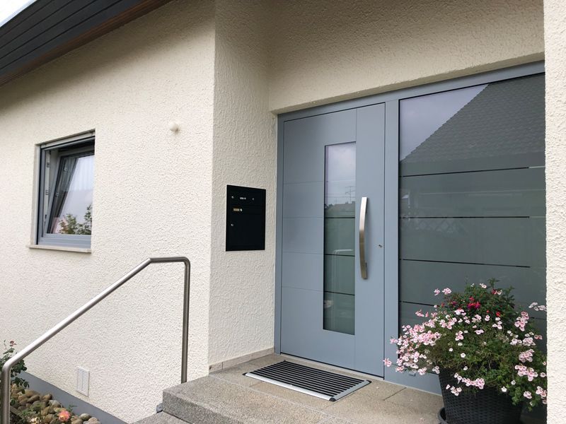 Ein weißes Haus mit einer blauen Tür und einem schwarzen Briefkasten