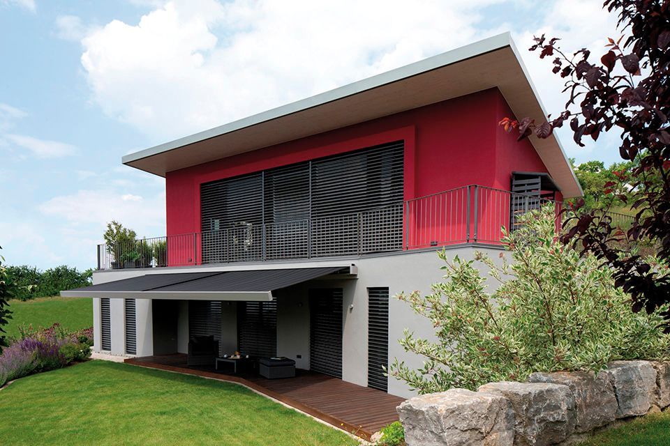 Ein rot-weißes Haus mit Balkon und Markise