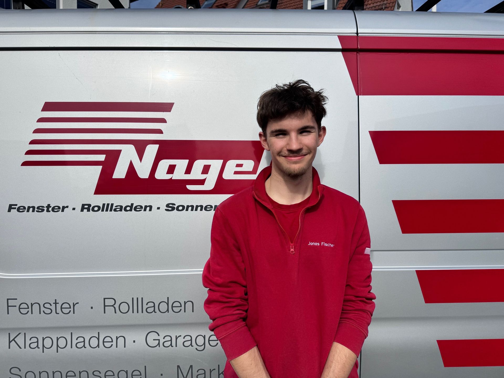 Ein Mann in einer blauen Jacke steht vor einem Nagelwagen.