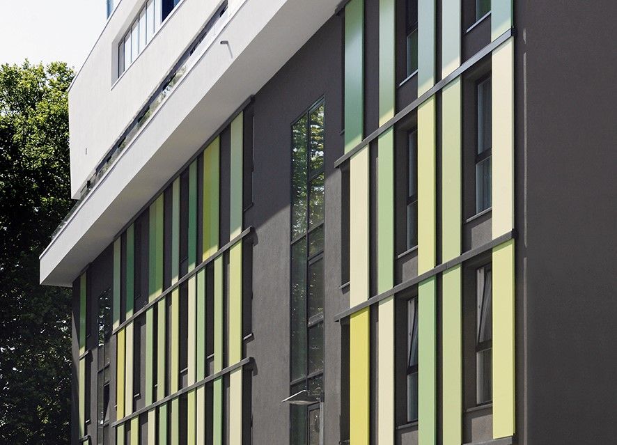 Ein Gebäude mit vielen Fenstern und grünen und gelben Fensterläden