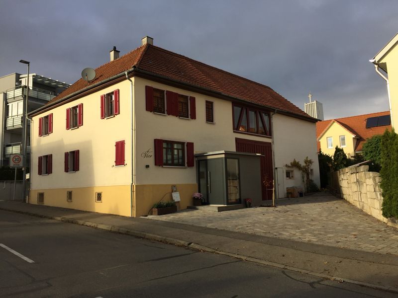 Ein weißes Haus mit rotem Dach und roten Fensterläden