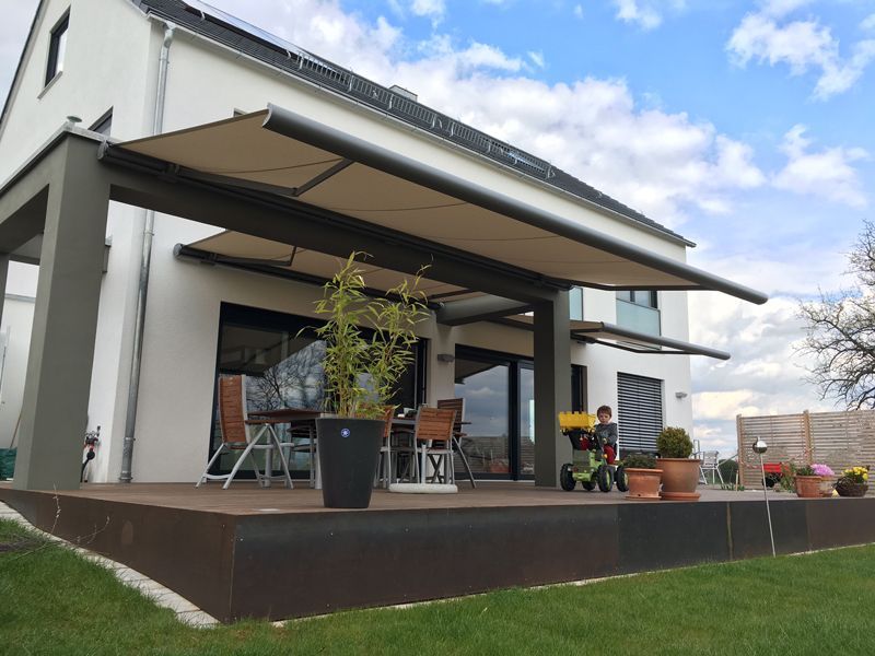 Ein weißes Haus mit einer großen Markise über der Terrasse
