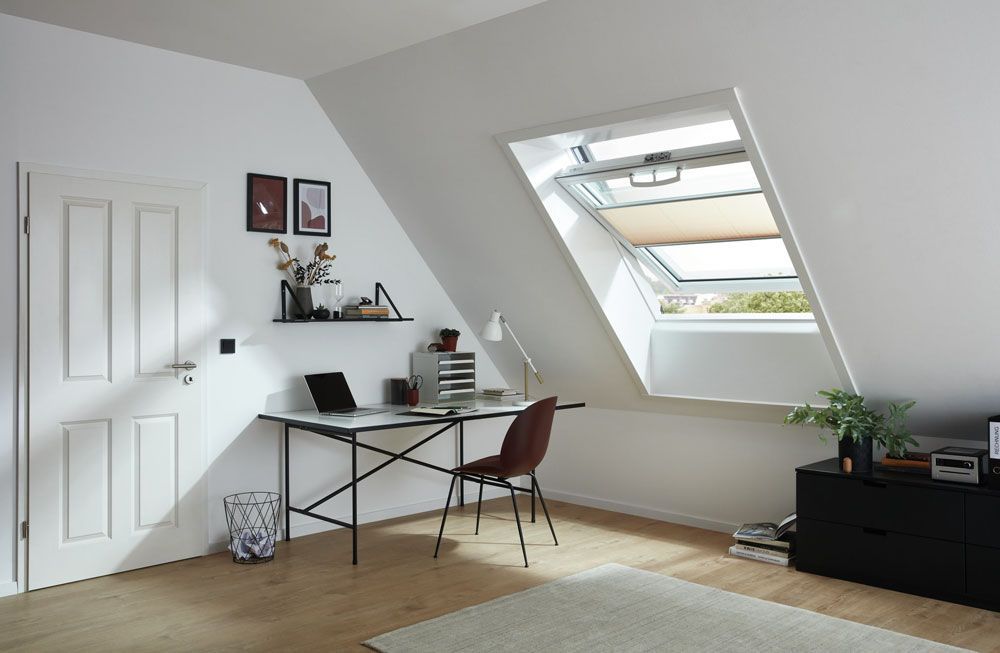 Ein Zimmer mit einem Schreibtisch und einem Stuhl sowie einem Oberlicht.